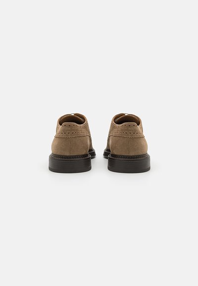 Brown suede shoes with a smooth texture, featuring brogue detailing, a rounded toe, and a dark, slightly elevated rubber sole.