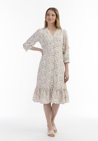 Floral Midi-Kleid aus leichtem Stoff mit V-Ausschnitt, Dreiviertelärmeln, Knopfleiste und gerafftem Saum. Farben sind Creme, Rot und Grün.
