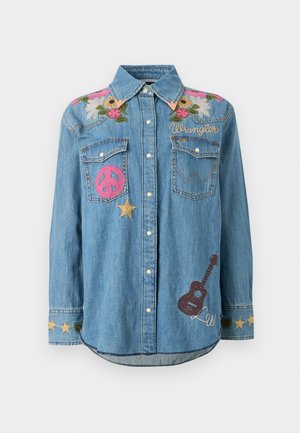 Τζιν πουκάμισο με κουμπιά, διακοσμημένο με κεντήματα λουλουδιών στους ώμους, ροζ έμβλημα ειρήνης, χρυσά αστέρια, κείμενο «Wrangler» και καφέ έμβλημα κιθάρας στο μπροστινό μέρος.