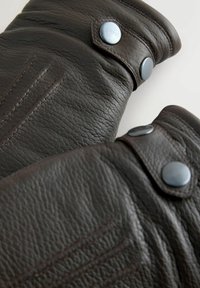 Dunkelbraune Lederhandschuhe haben eine strukturierte Oberfläche, Knopfakzente und gestickte Details. Die Bündchen sind gerollt und mit Druckknöpfen verschlossen.