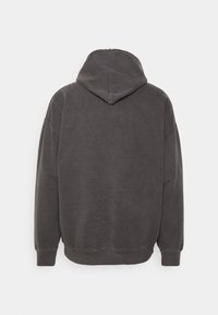 Felpa con cappuccio grigio scuro caratterizzata da una texture morbida, un design ampio, spalle scese e orli e polsini a coste. La vista dal retro mostra i dettagli del cappuccio.
