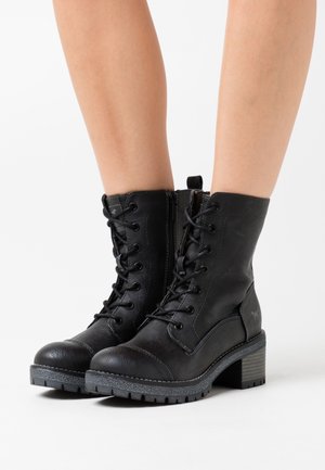 Bottes noires à lacets avec une tige en cuir texturé, un talon épais, une semelle en caoutchouc et une fermeture éclair latérale ; finitions mates et brillantes contrastées.