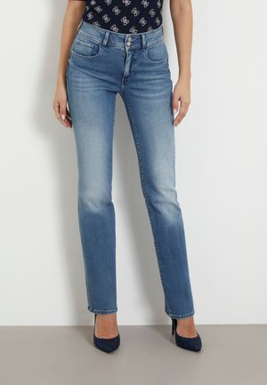 Jeans dritti in denim azzurro chiaro con dettagli sbiaditi. Presentano tasche frontali e una zip, abbinati a scarpe con tacco alte color blu navy.