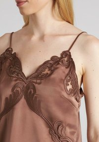 Camiseta de satén marrón con intrincados bordados oscuros en un diseño floral a lo largo del escote y las correas de los hombros. Textura suave, correas ajustables.