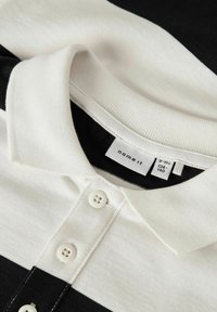 Valge ja mustriba polo särk valgete nuppudega ja kraega, sildil on br�änd "name it" ja suurus 9-10 aastat.