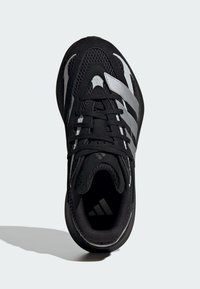 Čierna športová obuv s priedušným sieťovinovým zvrškom, striebornými pruhmi, polstrovaným golierom a plochými šnúrkami. Štruktúrovaná podrážka zabezpečuje priľnavosť a stabilitu.