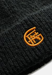 Zwarte gebreide muts met een gestructureerd oppervlak en een contrasterend oranje geborduurd logo, met een cirkelontwerp en strakke lijnen.