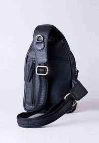 Black leather shoulder bag with a textured surface, featuring a zippered pocket, adjustable strap, and gold-tone hardware accents.