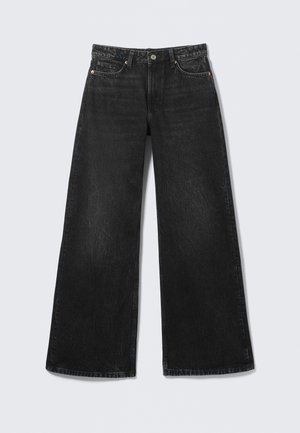 Zwarte jeans met wijde pijpen, vijf zakken en knoopsluiting, plat uitgestald op een lichte achtergrond.
