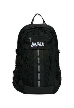 Zwarte Superdry rugzak met meerdere ritssluitingen, reflecterende verticale strip en bovenhandvat.