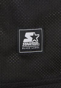 Svart mesh-stoff med en strukturert overflate. Har en hvit rektangulær etikett med "STARTER" og en stjerne-logo, samt "BLACK LABEL" i hvit tekst.