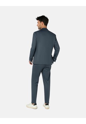 Men's suit in grey-blue fabric with a subtle pattern. Tailored fit, single-breasted jacket, matching trousers, and white sneakers.