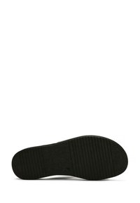 Suola di sneaker nera con una superficie testurizzata e rigata per la presa, un'area centrale liscia e una forma della punta arrotondata.