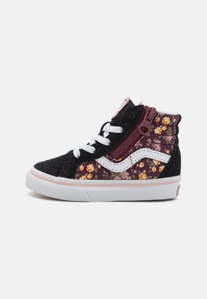 High-Top-Sneaker aus schwarzem Wildleder, mit floralen Stoffeinsätzen, weißen Schnürsenkeln, seitlichem Reißverschluss und weißem wellenförmigem Streifen auf weißer Sohle mit rosa Rand.