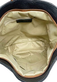 Zwarte leren handtas met een beige stoffen interieur, ritsvak en een soepele textuur. De opening heeft een gestikte tan accent.