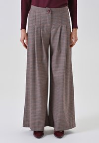 Breite kariertes Hosen in Braun und Creme, mit Falten, einer taillierten Taille und einem Knopfverschluss. Das Material hat eine glatte Textur.