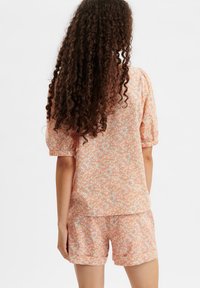 Completo da loungewear floreale composto da una maglia oversize e pantaloni corti, realizzato in tessuto leggero con colori pastello, maniche a sbuffo e polsini elasticizzati.