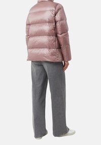 Padded puffer jacket w kolorze jasnoróżowym z błyszczącym wykończeniem, z poziomym pikowaniem. Połączony z szerokimi szarymi dżinsami i białymi sneakersami.