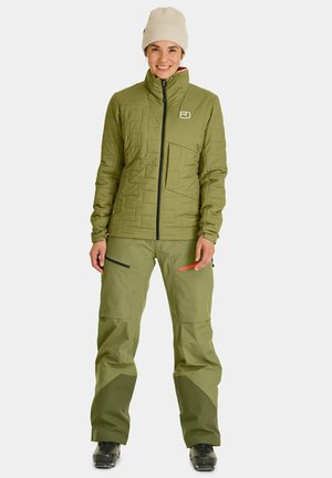 Olive green insulated jacket with quilted design, full zip, and prominent logo; paired with matching pants featuring zippered pockets and reinforced cuffs.