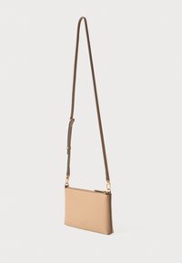 Borsa a tracolla in pelle color cioccolato con una texture liscia, sottile cinturino regolabile, hardware dorato discreto e chiusura con zip. Design minimale.