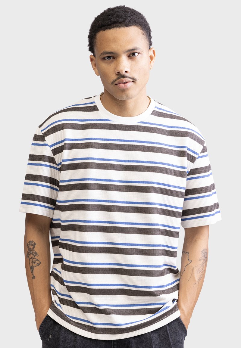 Striped t-shirt featuring horizontal lines in brown, blue, and white. Made of textured fabric with a crew neckline and short sleeves.