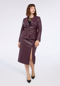 Burgunderfarbener Blazer aus Kunstleder mit taillierter Passform, kombiniert mit einem passenden Rock mit einem seitlichen Schlitz. Glatte Textur und eleganter Schnitt.