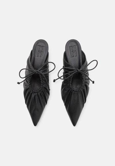 Black leather mules with a pointed toe, gathered texture, and bow detail. Features an open heel and embossed logo on the insole.