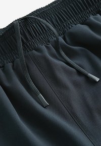 Black athletic shorts featuring an elastic waistband with a drawstring. The fabric has a smooth texture and minimal stitching details.