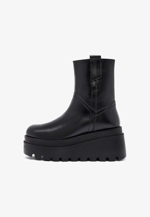Botas negras de cuero hasta el tobillo con un diseño elegante y minimalista. Suela de plataforma con goma texturizada para un mejor agarre y tirador en la parte posterior para mayor comodidad.