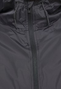 Veste noire imperméable dotée d'une fermeture éclair frontale complète, d'une capuche à cordon de serrage et de poignets élastiqués avec une texture lisse et mate.