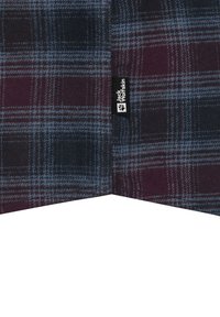 Tissu en tartan dans des tons de bleu foncé, bourgogne et gris ; texture douce ; comporte une étiquette de marque "Jack Wolfskin" sur le bord.
