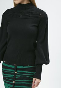 Schwarzer Strickpullover mit hohem geripptem Kragen, strukturiertem Body und gepufften Ärmeln. Verfügt über horizontale Details auf der Brust.