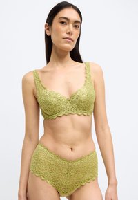 Roheline pitsist rinnahoidja ja sobivad kõrge vöökohaga püksikud, millel on sisselõigatud servad ja lillemustrid, esitledes pehmet ja tekstureeritud viimistlust.