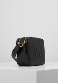 Černá kožená crossbody taška s embosovaným logem "RL". Má dva zlaté zipy a texturovaný povrch. Kompaktní čtvercový tvar s nastavitelným popruhem.