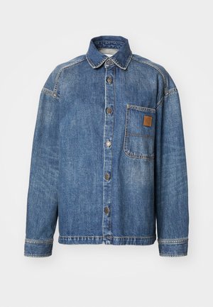 Veste en denim bleu clair avec une fermeture à boutons, col, manches longues, poche poitrine gauche et patch en cuir sur la poche.