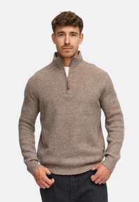 Herre kvart-zip trøje i lysebrun ribbestrik. Har lynlås foran, lange ærmer og en afslappet pasform med et sidetags med brand.