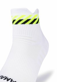 Calzino da ginnastica bianco con un design a coste, con un risvolto a righe nero e giallo neon. Il materiale sembra leggero e elastico.