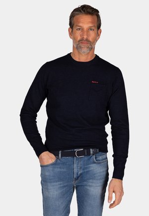Navyblauwe sweater met lange mouwen en een ronde hals, voorzien van een opgestikte zak. De trui heeft een rood geborduurd logo op de borst en is gemaakt van zachte stof.