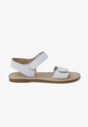 Sandalias de cuero blanco con dos correas ajustables de Velcro, punta abierta y suela plana marrón. Textura suave con diseño minimalista.