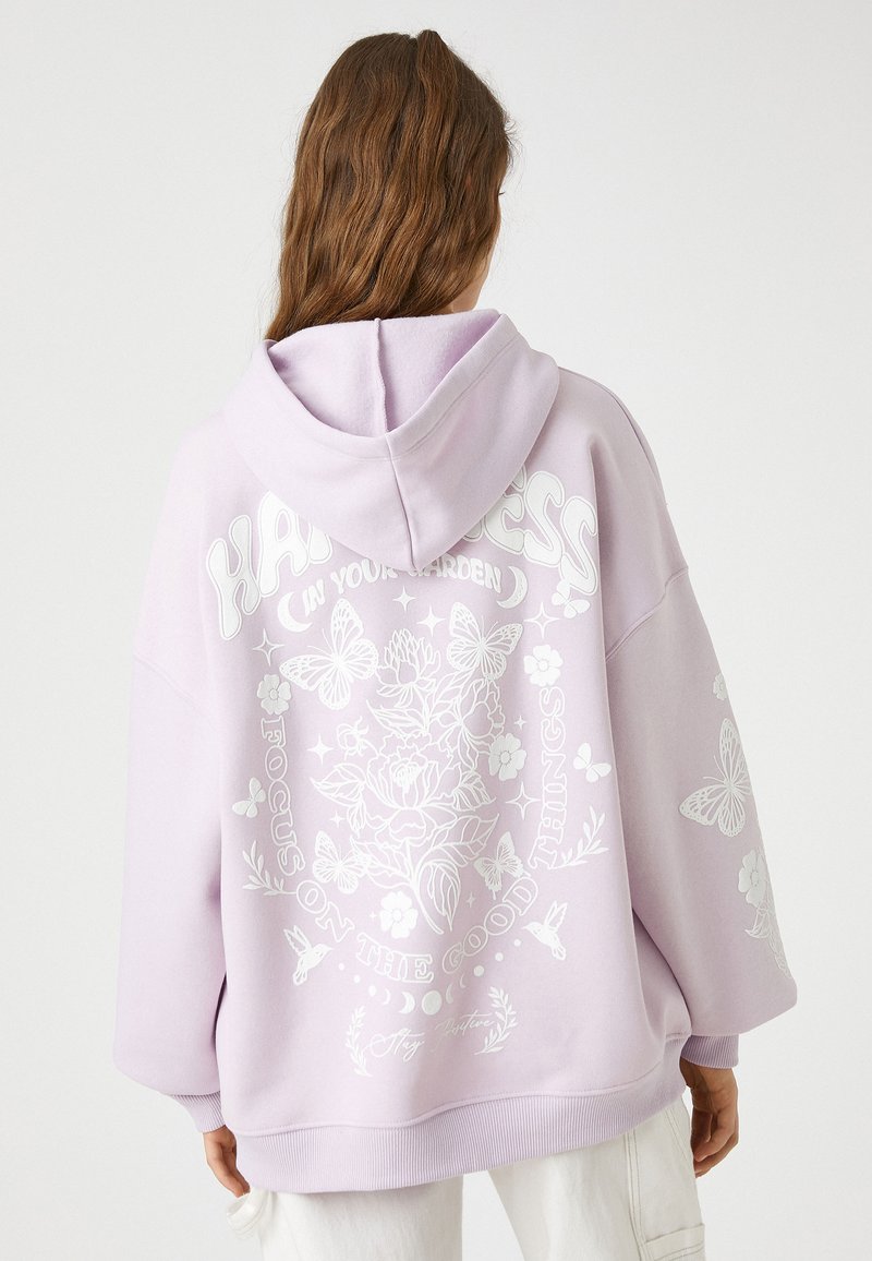 Przesadny hoodie w jasnym lawendowym kolorze, z białymi nadrukami kwiatowymi i motylkami. Zawiera kaptur ze sznurkiem i ściągacze na rękawach.