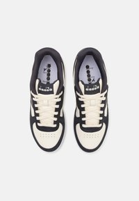 Scarpe sportive nere e crema con una tomaia in suede e sintetico, dotate di chiusura con lacci, perforazioni sulla punta e logo sulla linguetta.