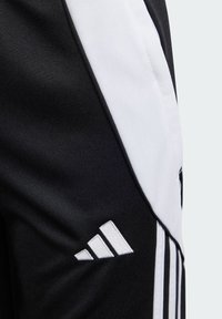 Zwarte sportbroek met een witte paneel, gestructureerde stof en een geborduurd wit logo met drie strepen op het onderbeen.