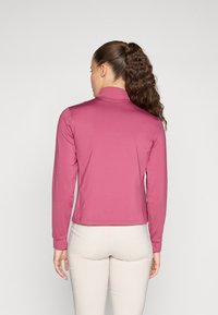Top a maniche lunghe e collo alto in un rosa intenso, realizzato in un materiale liscio. Presenta un design aderente con orlo corto e senza motivi visibili.