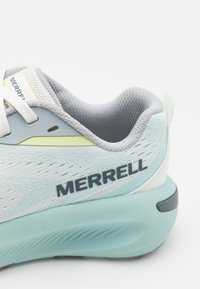 Lys blå treningssko med mesh-overdel, grå detaljer, fremtredende "MERRELL"-merkevare og en polstret såle. Har et strømlinjeformet design.