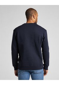 Mörkblå bomulls-huvtröja med ribbad rundhals och ärmslut, med en enfärgad design och avslappnad passform. Synliga sömdetaljer.