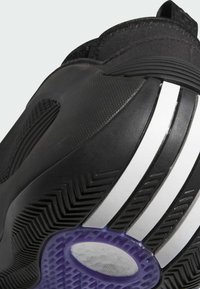 Czarne buty sportowe z teksturowaną cholewką, z białymi paskami i fioletową podeszwą z bieżnikiem w jodełkę dla lepszej przyczepności. Wzmocniony czubek.