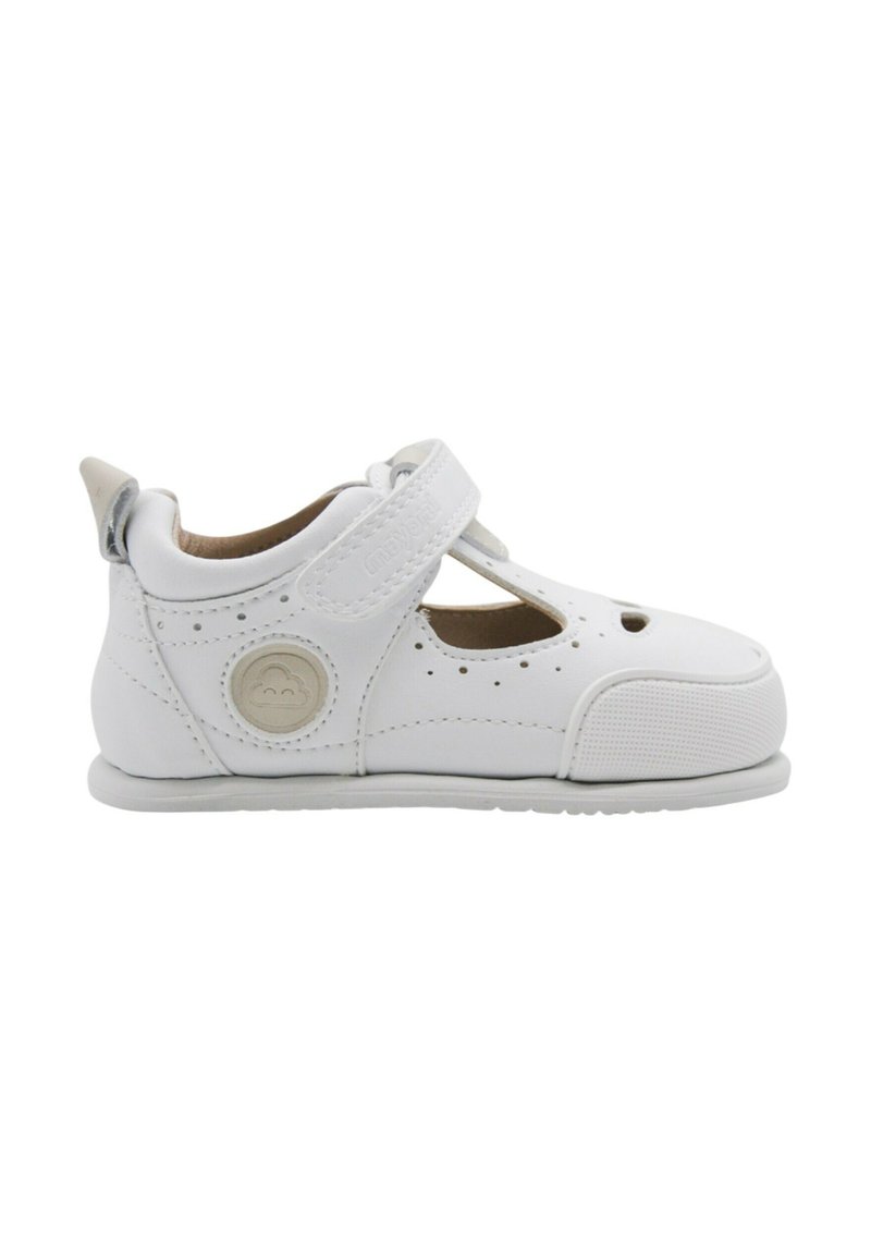 Zapato infantil de cuero blanco con detalles troquelados, correa de Velcro, punta redondeada, suela texturizada y acento de logo circular en el lateral.
