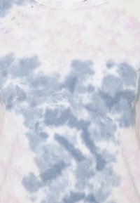 Blød lyserød og blå tie-dye mønster på let stof med en rund halsudskæring, der viser en nærbillede af et garments øverste sektion.