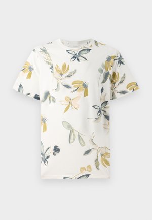 T-shirt a maniche corte in cotone bianco, con un motivo floreale caratterizzato da accenti verdi, gialli e blu sparsi su tutto il tessuto.
