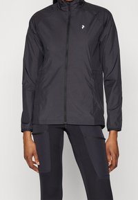 Veste noire légère avec un col montant, une fermeture éclair complète, deux poches latérales et un petit logo sur le côté gauche de la poitrine. Fabriquée en matière lisse et résistante à l'eau.